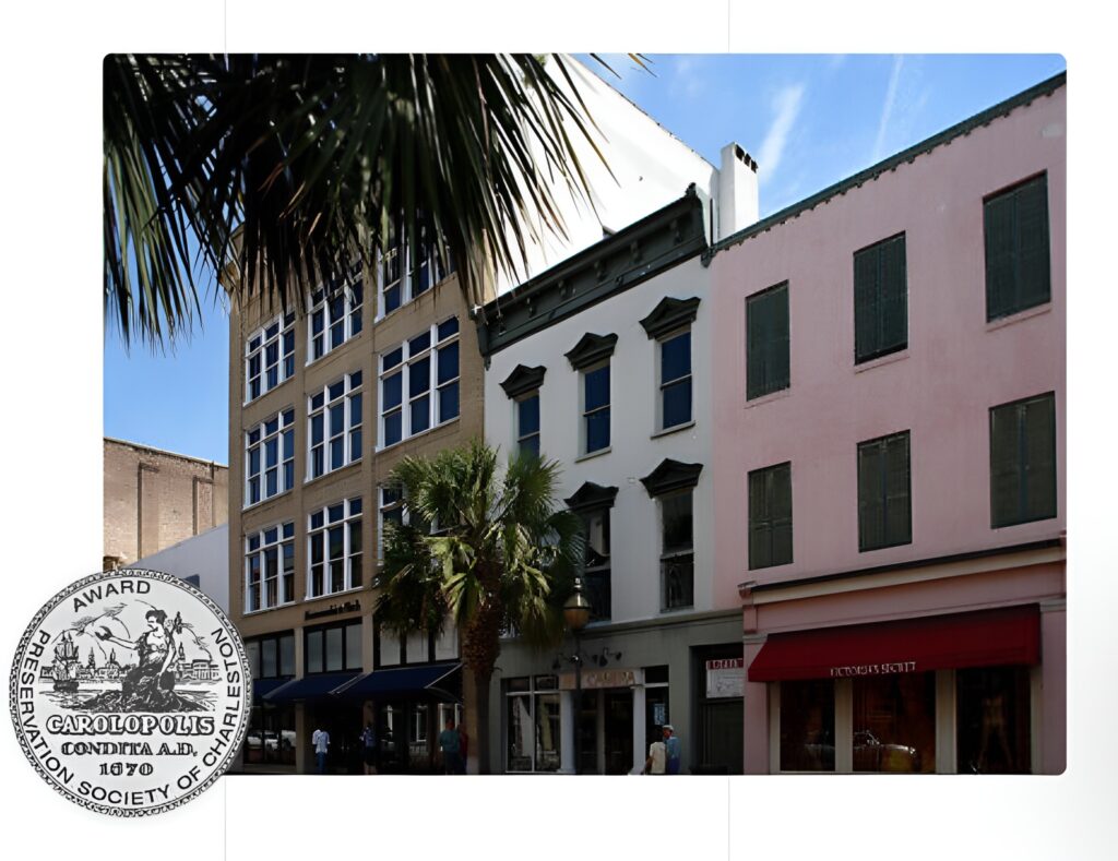 A row of historic buildings with colorful facades and green window shutters line a sunny street with palm trees. A Carolopolis Award medallion is displayed in the lower left corner.